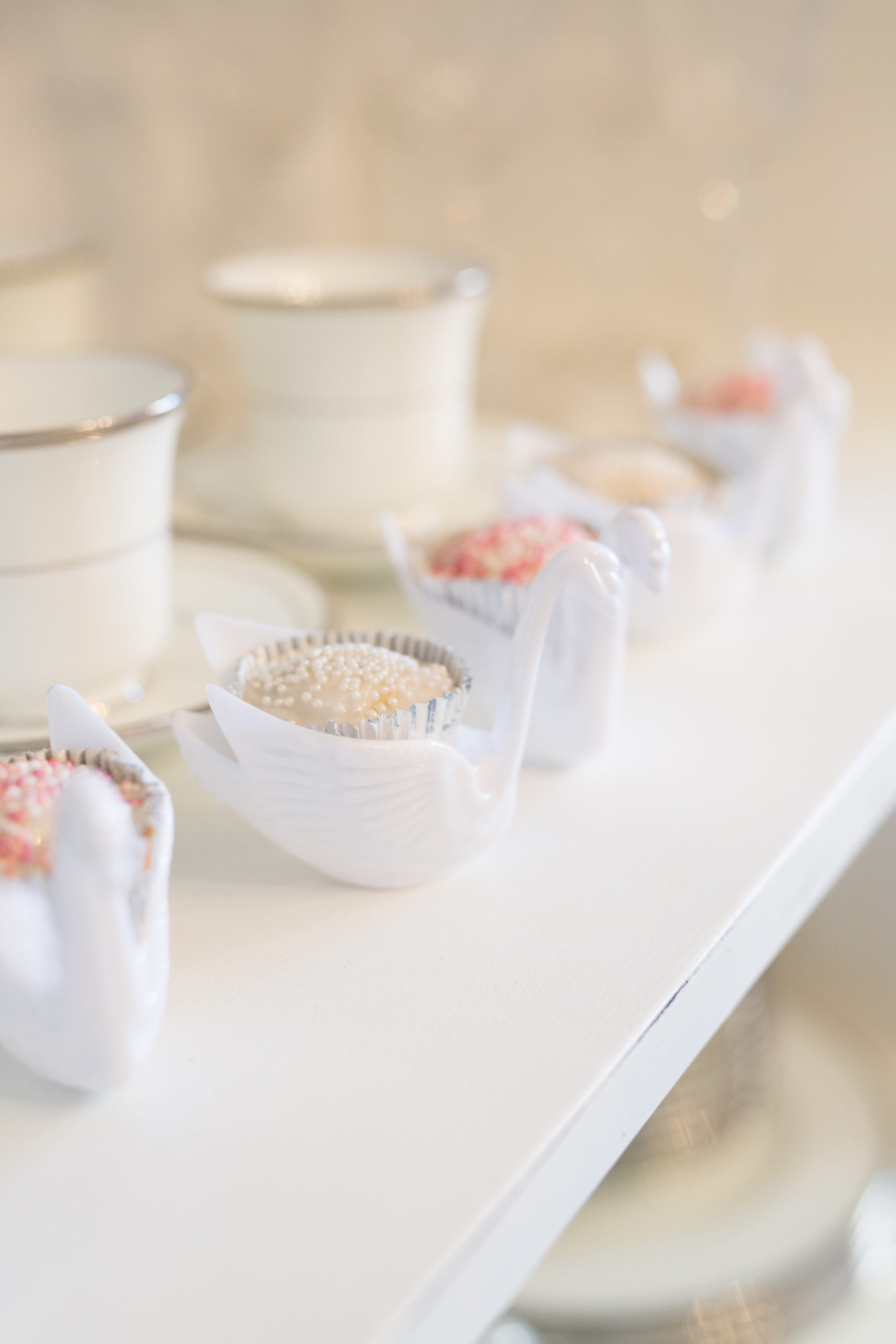 Pretty white and pink cupcake treats nestled in swans for the baby welcome