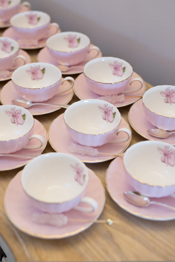 Elegant pink teacups with sugar crystal sticks and silver teaspoons for a welcome to the world baby celebration