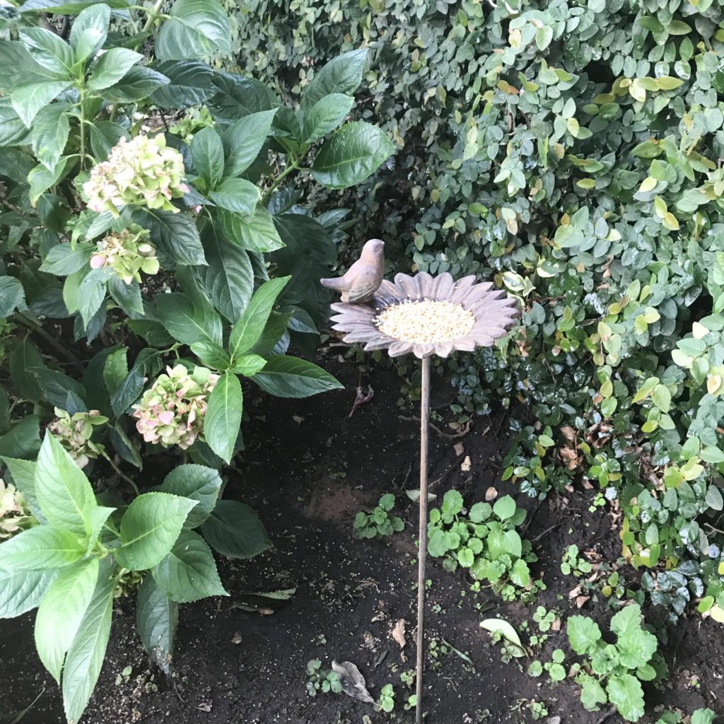 Standing bird feeder in flowerbed