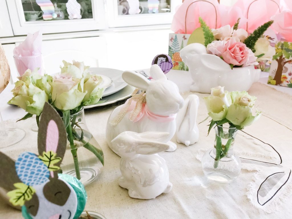 White ceramic bunnies and pale pink roses for pastel Easter table decor