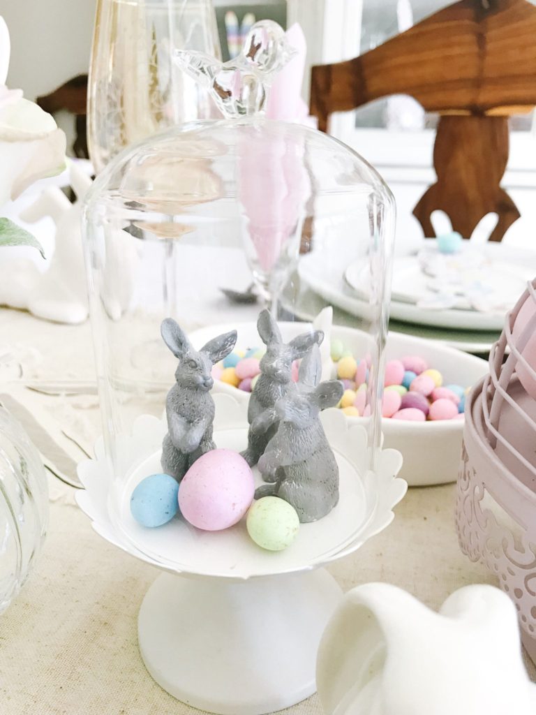 Three grey bunnies with speckled eggs in small glass cloche