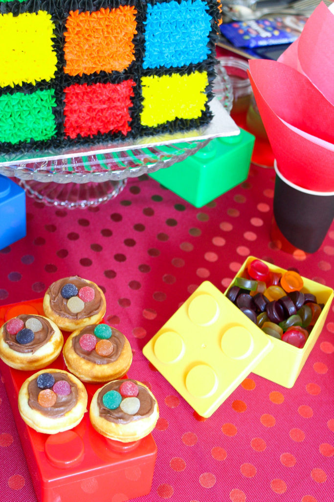 Mini donuts and brightly coloured sweets on the birthday table of this Rubik's cube inspired party